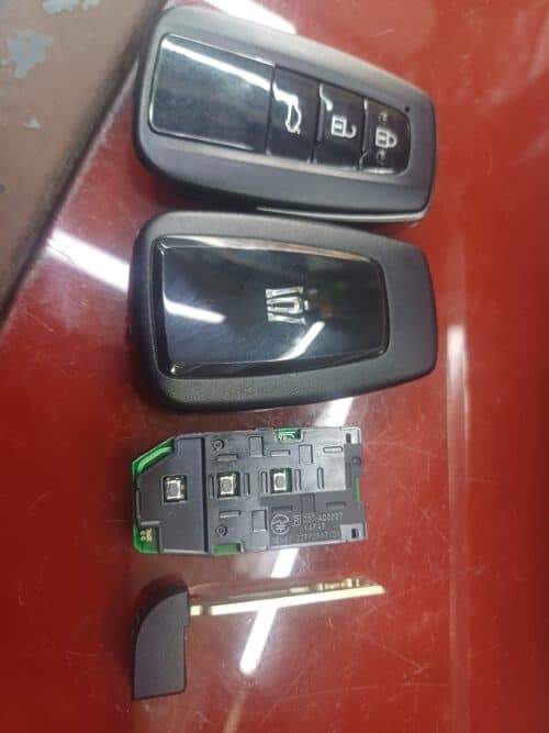 Car key fob with lock, unlock, and trunk buttons, alongside an electronic control module and a key b.