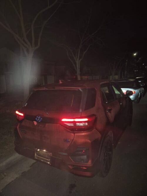Toyota RAV4 parked at night on a dark street with trees in the background.