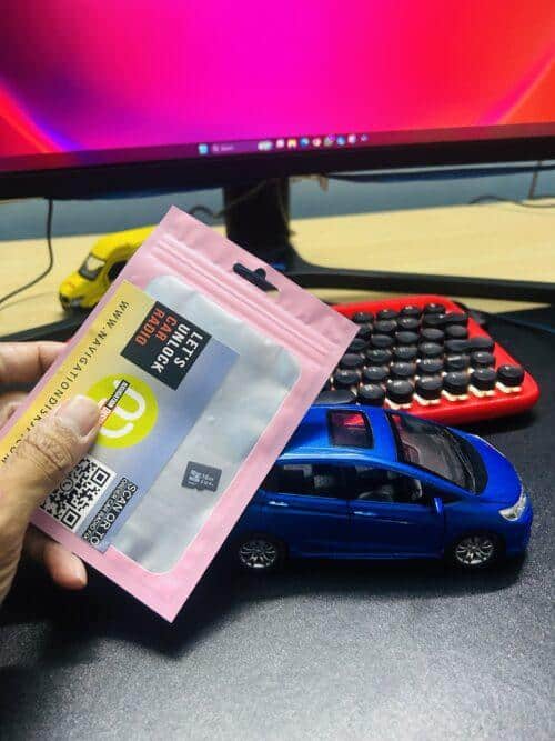 Portable navigation disk for car GPS with QR code, on desk with computer and toy car.