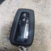 Car key fob with lock and unlock buttons on a textured surface.