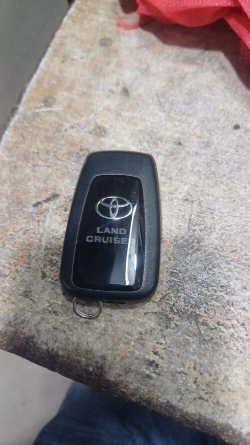 Toyota Land Cruiser key fob on a workbench surface.