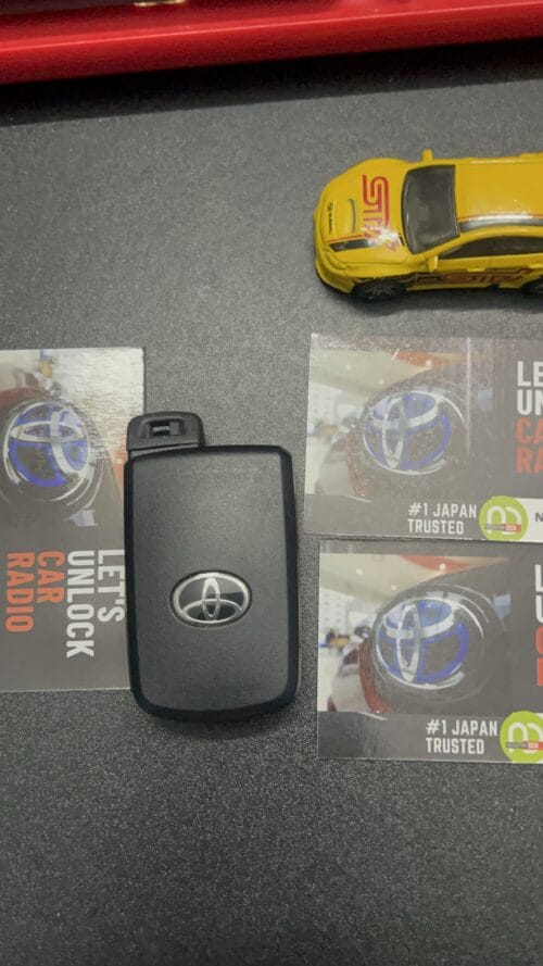 Car key with Toyota logo and promotional cards on a black surface.