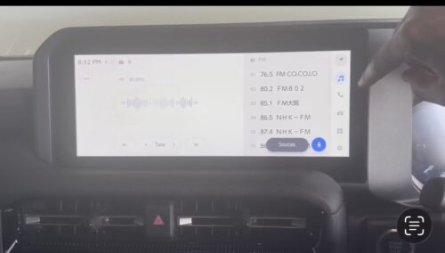 In-car multimedia system displaying radio station list and audio controls.