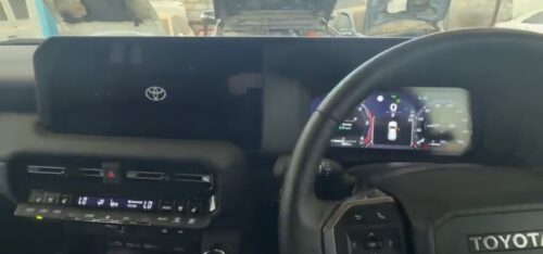 Modern Toyota vehicle dashboard with digital speedometer and steering wheel.